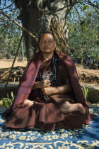 Portrait of Buddhist monk from The Golden Horse Forest Monastery meditating in the lotus position beneath tree.Thai/Burmese border.Abbot Kru Ba.