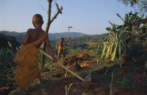 Novice Buddhist monks from The Golden Horse Forest Monastery working on land breaking up soil.Thai/Burmese border.