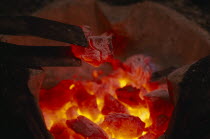 Close up of glowing hot coals and tongs in a hibachi Thai charcoal brazier