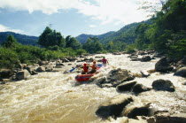 Western tourists and Thai guides white water river rafting on the Mae Taeng River