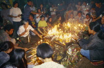 Inthakhin Ceremony. People lighting candles on offerings table