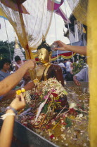 Inthakhin Ceremony. Bathing Phra Fon Saen Ha Buddha statue surrounded by floral offerings and pool