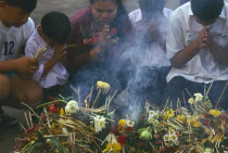Inthakhin Ceremony. People praying in front of offerings of flowers and joss sticks