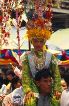 Shan Poi San Long. Crystal Children ceremony with Luk Kaeo in costume sitting on mans shoulders at Wat Pa Pao