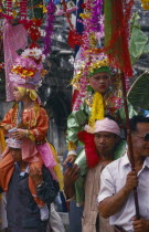 Shan Poi San Long. Crystal Children ceremony with 2 Luk Kaeo in costumes sitting on mens shoulders at Wat Pa Pao