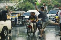 Songkran aka Lunar New Year. Revellers in a pickup truck attempting to catch some of the water thrown at them over the heads of motorcyclistsLorry