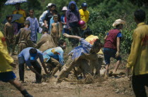Young men frolicking in a mud pool during the Rocket Festival Bun Bang Fai