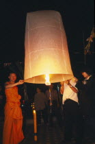 Loi Krathong Festival aka Yi Peng. Monk and other people launching hot air balloon into the night sky