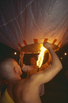 Loi Krathong Festival aka Yi Peng. Monk and another man launching hot air balloon into the night sky