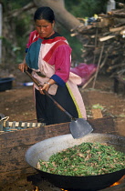 Lisu woman stir frying meal in large wok for New Year dinner