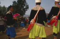 Lisu man carrying offerings to put by the New Year tree surrounded by dancers
