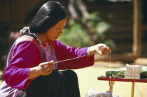 Lisu woman preparing string to be tied on familys wrists for good luck at New Year