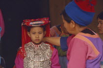 Young Lisu girl dressed in her New Year finery while her mother adjusts her silver neck chain