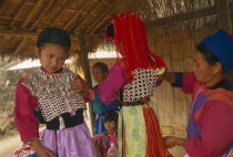 Young Lisu girls dressed in their New Year finery while their mother adjusts their vests