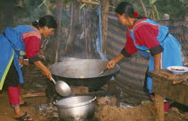 Lisu women stir frying a meal in a large wok for New Year dinner
