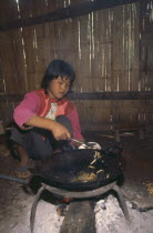 Lisu girl putting cooked bamboo grubs in a bowl in her kitchen