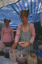 Two Shan women in traditional Shan attire at a food shop during Poi Sang Long