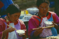 Two Lisu women eating at the village priests house for the New Years festival