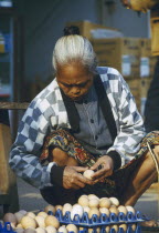 Elderly woman selecting eggs to purchase at the morning market