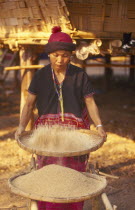 Sgaw Karen woman sifting rice with a large bamboo tray