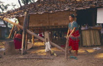Sgaw Karen woman using a foot powered rice pounder to remove husks