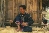 Red Lahu man shaving bamboo into strips