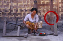 Jinghpaw woman spinning thread onto a bobbin for weaving at a weavers shop Burma