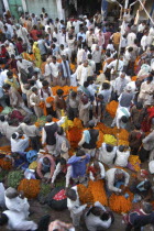 View looking down on busy flower market with a majority of male vendors selling mostly marigolds