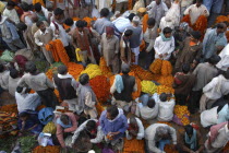 View looking down on busy flower market with a majority of male vendors selling mostly marigolds