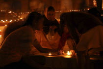 Deep Divali Festival with young girls lighting oil lamps on steps leading down to the Ganges River