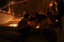 Deep Divali Festival with young girls lighting oil lamps on steps leading down to the Ganges River