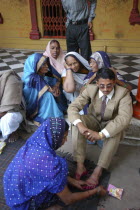 Sankat Mochan Mandir temple. Hindu wedding with the groom getting his feet painted auspicious red as his mother sits behind him