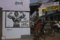 A young Arnold Schwarzenegger painted on a poster for underwear with rickshaw driver nearby