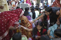 Sankat Mochan Mandir temple. Women friends and relatives comfort and cheer a bride in a red and gold sari at her wedding outside the temple