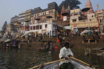 A boatman bringing his boat into Dashaswamedh Ghat with early morning bathers in the Ganges River
