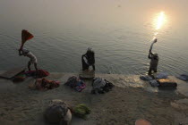 Near Shivala Ghat. Dhobi clothes washers working on the banks of the Ganges River with low sun on the horizon