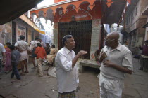 Bengali Tole. Two middle aged men have a morning coversation outside a temple using their hands to stress the points they are makinghand gestures