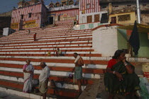 Hindu worshippers on the steps of Kedar Ghat next to the Ganges River with steps leading up to Kedara Mandir temple in the early morning