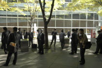 Yurakucho. A group of male salaried workers called salariman  smoking at a smoking station  during lunch hour at Tokyo International Forum