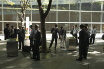 Yurakucho. A group of male salaried workers called salariman  smoking at a smoking station  during lunch hour at Tokyo International Forum