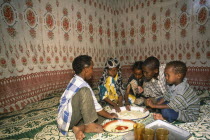 Children eating meal at home from communal dish using the right hand.  At a family meal men are usually served first and women and children eat seperately later.