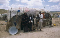 The Kandahr IDP camp for Internally Displaced Persons.  Family standing outside traditional nomadic hut.Ayaha returnee settlement