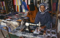 Female trader at sewing machine in market.