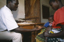 Refugee camp health centre.  Male staff with woman and child.Center