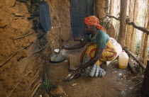 Refugee woman cooking on wood saving clay stove inside hut with mud brick walls.Refugees from the Congo and Rwanda fleeing conflict in Burundi Zaire