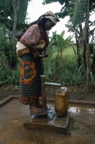 Woman with baby tied on her back collecting water from pump in refugee camp.Refugees from the Congo and Rwanda fleeing conflict in Burundi Zaire