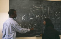 Teacher and pupil writing letters on blackboard at school for returnees in Kandahar settlement.Ayahar