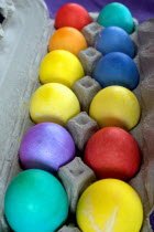 A dozen dyed Easter eggs in a carton.