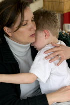 Mother comforting son after a playtime incident. Ages 34 and 4