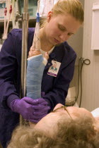 Clinic nurse forming cast on arm of elderly patient with broken wrist.Age 28 and 90.